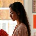 Portrait of Aisha Rahman, a textile pattern artist, in a studio with design sketches and fabric swatches